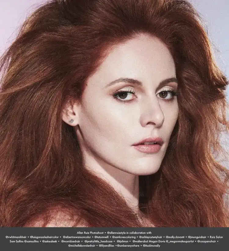 Red-haired woman with striking makeup, looking directly at the camera.