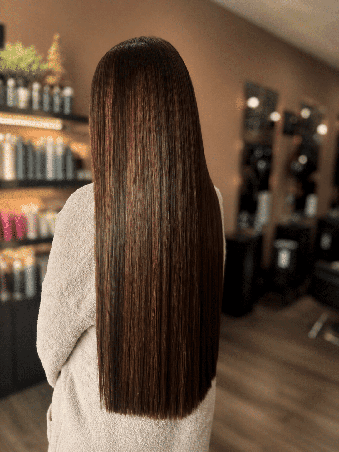 Straight-haired woman in salon, showcasing sleek, healthy brown hair.