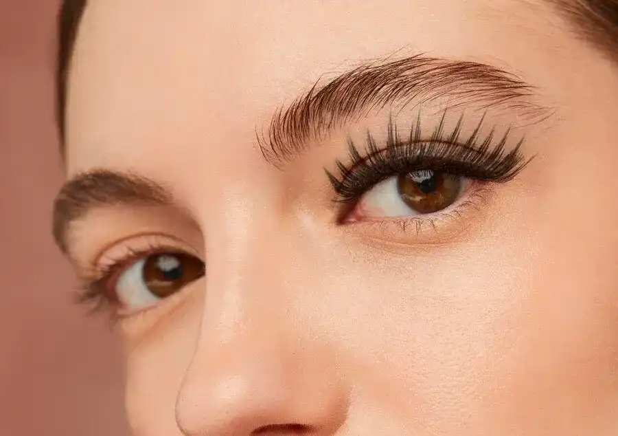 Close-up of a person's eyes with dramatic, bold eyebrow and eyelash makeup.